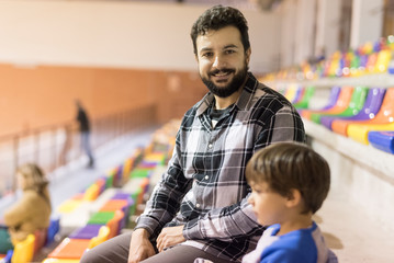 Father and son in bleachers looking sport event