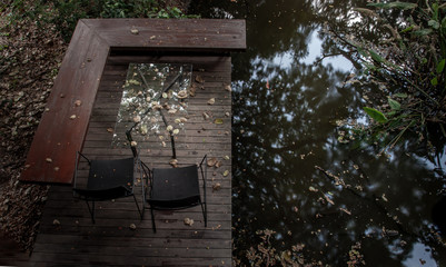 Relaxing area with two chairs and glass table in the garden over the small canal.