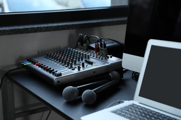 Modern audio mixing console and microphones on black table indoors. Music equipment