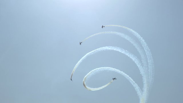 Clear blue sky four planes perform aerobatics: take off, make a loop, twist a spiral Leave a pattern in the sky