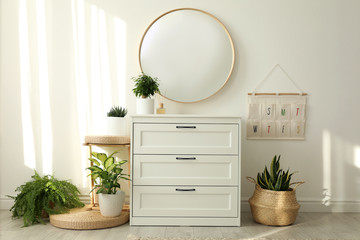 Stylish room interior with chest of drawers and round mirror