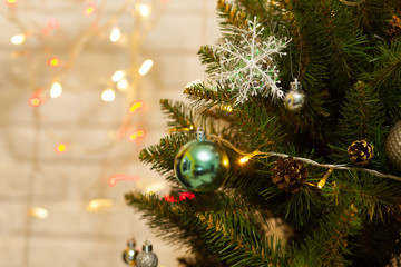Beautiful green Christmas tree decorated with balls and garlands. Close-up photo. Sparkling background