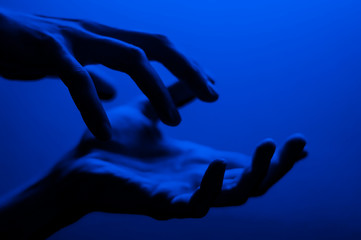 Obraz na płótnie Canvas Hands in monochrome blue contrast neon light. Man showing hand palm gesture sign. Artistic photography.