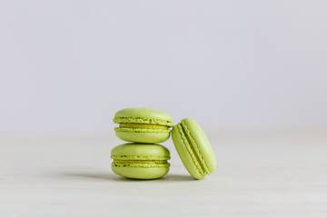 Three light green french macarons on a  wooden table. Pistachio macarons.