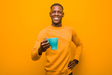 young african american black man against orange wall with a coffee cup