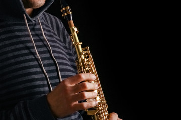 soprano saxophone in the hands of a guy on a black background