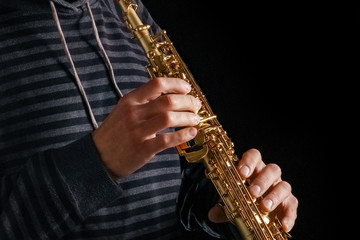 soprano saxophone in the hands of a guy on a black background
