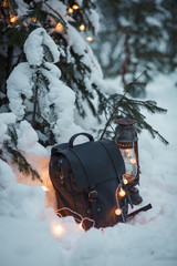 Winter composition with lamp, backpack and garland with bokeh. Concept in snow