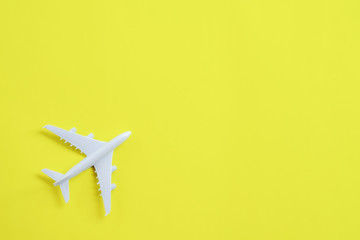 Miniature toy airplane white on yellow background.