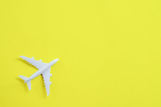 Miniature toy airplane white on yellow background.
