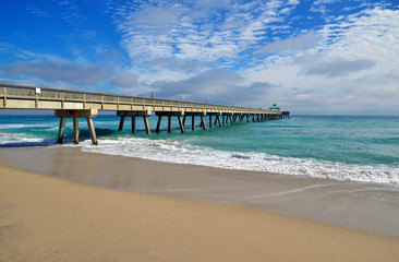 Seashore landscape with fishing pier with beach and waves in Atlantic Ocean in Florida