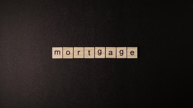 Closed Wooden cubes open and sets up a word "Mortgage" on a black table