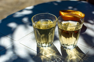 White wine served outside in garden on white table with fresh orange in sun lights