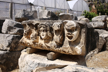 Antique theater masks carved on the stone part of an ancient building. Archaeological site in the city of Demre, Turkey.