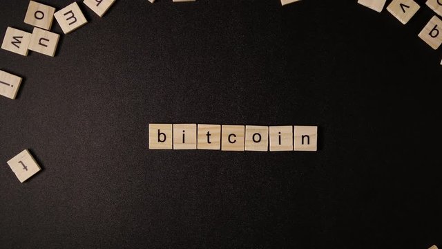 Letters move and sets up a word «Bitcoin» on a black table 