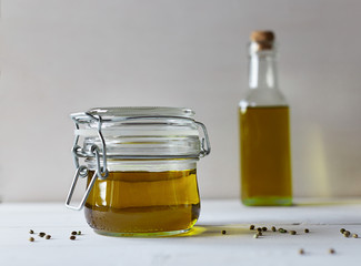 Hemp oil in a glass bottle and seeds on a white wooden background. Horizontal photo.