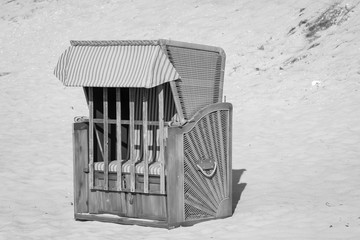 ein verschlossener Strandkorb steht einsam am Strand der Ostsee