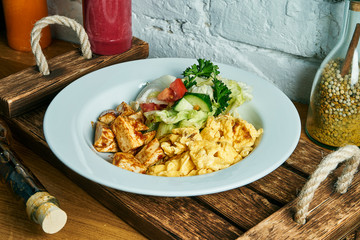 Healthy and nutritious breakfast - scramble omelet with tofu and vegetables in a white bowl on a wooden board