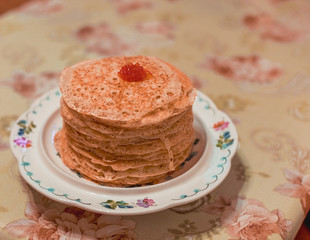 a stack of lace pancakes with red caviar lies on a porcelain stand on a table. food photo. Maslenitsa.