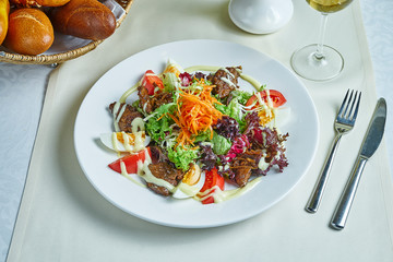 Salad with warm chicken, tomatoes, lettuce, egg and carrots on a white plate. Restaurant serving. Delicious Snack Food