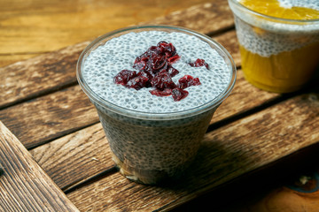 Vegetarian healthy dessert trifle white vanilla pudding chocolate and cherry in a plastic container on a wooden background