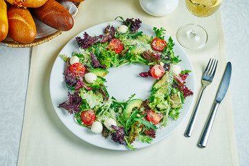 Fresh and healthy Salad with avocado, cherry and mozzarella on a white plate. Restaurant serving dishes. Top view, flat lay food.