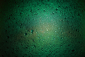 green oil droplets from a mixture of water and olive oil illuminated with green colored bulb
