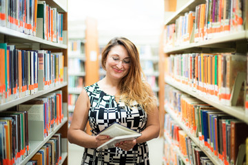 Beautiful white woman female student smiling and reading book. She is standing near, between...