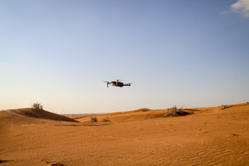 Eine Drohne fliegt in der Abendsonne in der Wüste