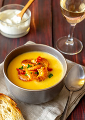 Cheese cream soup with grilled shrimp on a wooden background.