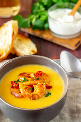 Cheese cream soup with grilled shrimp on a wooden background.