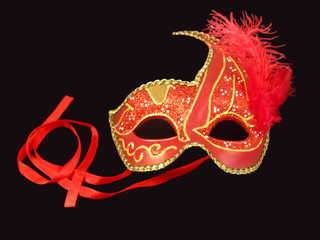 Red venetian carnival mask isolated on a black background. The concept of a party, fun, games, celebrations, carnival, theater, masquerade, New Year's corporate party. Symbol of mystery and secret.