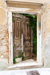 Old wooden door on the ruined wall of an abandoned house