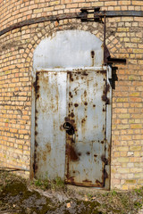 Heavy industrial rusty door in old warehouse against a brick wall