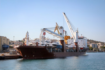 Fototapeta premium Ein großes Transportschiff ist mit einigen Yachten beladen
