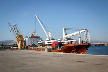 Ein großes Transportschiff ist mit einigen Yachten beladen