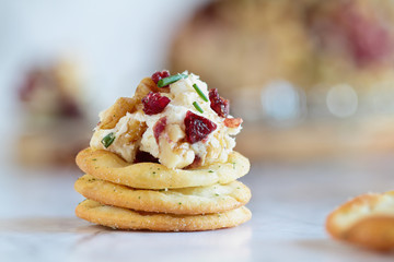 Fresh homemade cranberry cheese spread made with cream cheese, white cheddar, dried cranberries, walnuts, and chive over marble table. Selective focus with blurred background 