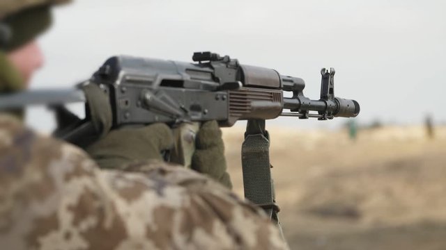 Military man firing from AKS 74 with a folding stock in a range in slo-mo