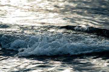 Small waves break before reaching the beach at sunset