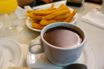 Churros, hot chocolate and orange juice on a table in a cafe 