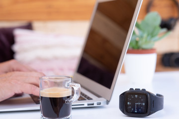 Close up view of a computer with two hands working on it. Coffee cup. Outdoor alternative office for a freelance worker