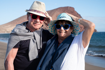 Windy day at the sea. One retired couple of people enjoying the beach in autumn or winter. Tropical place with blue sea and red mountain