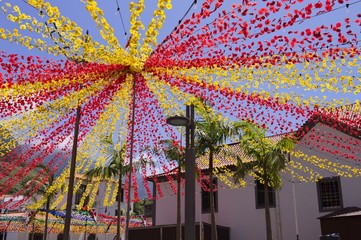 Decorations with red and yellow colored paper flowers in the square for a traditional festival (Sao Vicente, Madeira, Portugal)