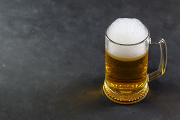 Beer in a mug with water drops on wooden table on dark background.
