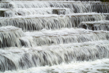 Water Cascading over Weir Steps on canal slipway showing blur blurred motion and freeze frame of water droplets for background tectures and layer effects