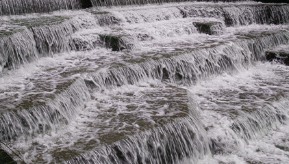 Water Cascading over Weir Steps on canal slipway showing blur blurred motion and freeze frame of water droplets for background tectures and layer effects