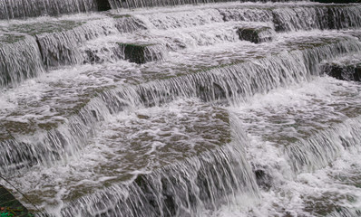Water Cascading over Weir Steps on canal slipway showing blur blurred motion and freeze frame of water droplets for background tectures and layer effects