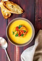 Cheese cream soup with grilled shrimp on a wooden background.