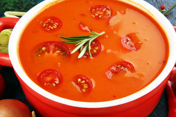 Tomato and fresh rosemary soup with garlic, cracked papper corns, served with cream. Homade tomato soup for dinner