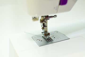 thread tucked into a needle from a sewing machine